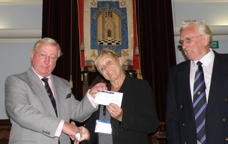 Mrs Joyce Steele receiving the £1000 cheque from Lodge Charity Steward, WBro Tony Norman with Lodge Almoner, WBro John Walsh, looking on Mrs Joyce Steele receiving the £1000 cheque from Lodge Charity Steward, WBro Tony Norman with Lodge Almoner, WBro John Walsh, looking on